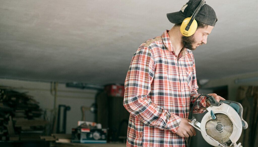 A focused young handyman operating a circular saw in a workshop.