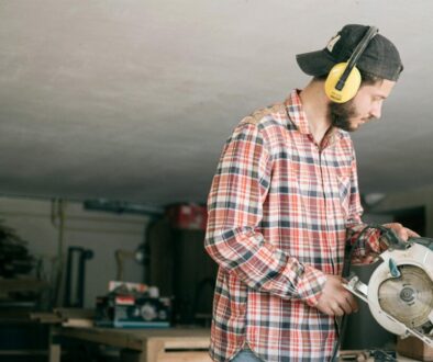 A focused young handyman operating a circular saw in a workshop.
