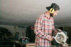 A focused young handyman operating a circular saw in a workshop.